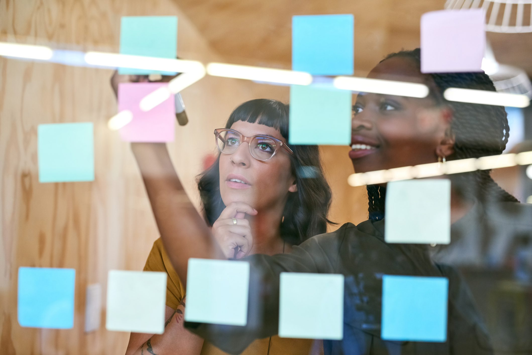 Two women brainstorming ideas on coloured sticky notes